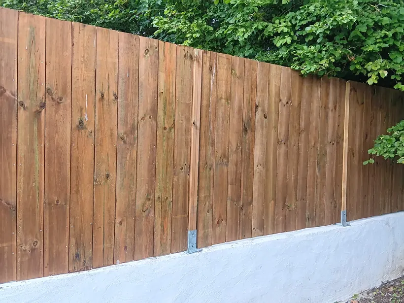 Clôture en bois posée sur muret enduit, en limite de propriété